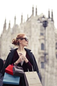 Fashionable woman holding shopping bags in front of Milano Cathedral in Italy.